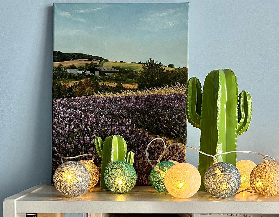 A painting of a landscape on top of a desk surrounded by cacti and decorations. 